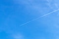 Jet aircraft flying on the high altitude against the backdrop of a clear blue sky. Airplane with two condensation trail on clouds Royalty Free Stock Photo