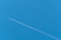 Jet airliner flying high in the sky leaves contrails in the clear blue sky Royalty Free Stock Photo