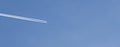 jet airplane in a sky with white trace. banner, copy space. travel and air cargo concept. low angle view Royalty Free Stock Photo