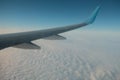 Jet airplane wing flying over cloud cover in blue sky in daytime Royalty Free Stock Photo