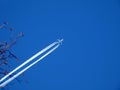Large 4 engine jet in blue sky with white contrails