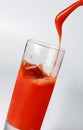 A jet of fresh tomato juice filling a glass. Close-up.