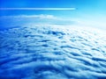 Jet plane contrail in blue sky above the clouds