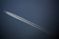 Jet plane flies high in the blue sky, leaving behind a jet trail Royalty Free Stock Photo