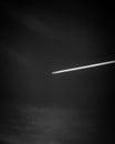 a jet plane flying into the dark sky with its contrails coming through Royalty Free Stock Photo