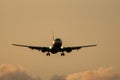 Jet plane landing against clouds at sunset Royalty Free Stock Photo