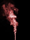 A jet of red smoke curls and swirls and rises up against a black