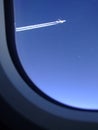 Jet trails of an airliner which was flying alongside seen through the window of my plane Royalty Free Stock Photo