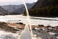 A jet of water flows down onto an ice block, on the bank of a mountain river in the early winter evening Royalty Free Stock Photo