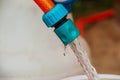 A jet of water from a hose fills a plastic barrel. Background image. The concept of the drinking water crisis in the world