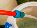 A jet of water from a hose fills a plastic barrel. Background image. The concept of the drinking water crisis in the world