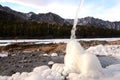 A jet of water pours onto an ice block on the bank of a frozen mountain river in early winter Royalty Free Stock Photo