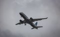 JetBlue Airbus A220 aircraft flying through the sky on a grey cloudy day