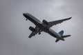 JetBlue Airbus A220 aircraft flying through the sky on a grey cloudy day