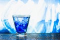 Jets and waves of blue water in a glass on a dark table with blue spangles stars on an abstract background ice mountains Royalty Free Stock Photo