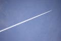 Jetstream follows white plane three quarters of the way across a blue mottled sky Royalty Free Stock Photo