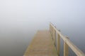 A jetty disappears into a mist covered lake