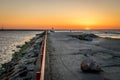 A jetty or pier with silhouetted people with a sunset at sea. Royalty Free Stock Photo