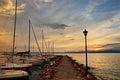 Promenade at pier with sailboats by romantic sunset sky, lake Garda landscape Royalty Free Stock Photo