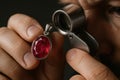 A jeweler closely inspects a ruby pendant using a magnifying loupe in a precise gemstone evaluation process Royalty Free Stock Photo