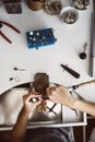 Jeweler`s workplace. Top view of jeweler`s workbenche with different tools on a white table. Female hands making a new