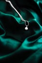 Luxury white gold pearl necklace on dark emerald green silk background, holiday glamour jewelery present Royalty Free Stock Photo