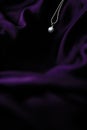 Luxury white gold pearl necklace on dark violet silk background, holiday glamour jewelery present Royalty Free Stock Photo