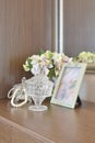 Jewelry crystal jar with picture frame and flowers on wooden table