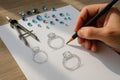 A jewelry designer sketching elegant ring designs surrounded by gemstones and precision tools, capturing the creative process of Royalty Free Stock Photo