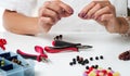 Jewelry making. Making bracelet of colorful beads. Female hands with a tool. Royalty Free Stock Photo