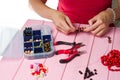 Jewelry making. Making bracelet of colorful beads. Female hands with a tool on a pink Royalty Free Stock Photo