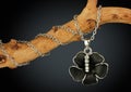 Jewelry pendant shape of black flover on twig, on dark background Royalty Free Stock Photo