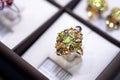 Jewelry retail store showcase displaying white gold ring with precious gemstones. ring with emeralds, citrines, topazes. close