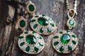 Jewelry set, earrings and pendant with green stones on a wooden background Royalty Free Stock Photo