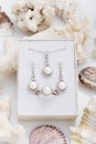 Jewelry set of elegant silver earrings, ring and pendant necklace with pearl and diamonds in gift box on coral