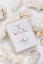 Jewelry set of elegant silver earrings, ring and pendant necklace with pearl and diamonds in gift box on coral Royalty Free Stock Photo