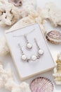 Jewelry set of elegant silver earrings, ring and pendant necklace with pearl and diamonds in gift box on coral