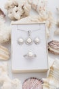 Jewelry set of elegant silver earrings, ring and pendant necklace with pearl and diamonds in gift box on coral Royalty Free Stock Photo