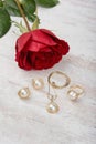 Jewelry set of golden ring, earrings, necklace with pearls and red rose on white wooden background Royalty Free Stock Photo