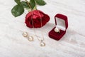 Jewelry set of golden ring in a gift box, earrings, necklace with pearls and red rose on white wooden background Royalty Free Stock Photo