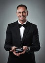 Jewelry, smile and portrait of a man giving a valentines present in a studio. Isolated, gray background and happy person