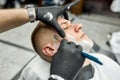 Jewelry work. Barber in black gloves shaving young handsome man with dangerous straight razor. Working n barbershop Royalty Free Stock Photo