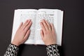 Jewish book, with woman`s hand, on black background. Text of the Hebrew, prayer. Woman prays with book.