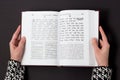 Jewish book, with woman`s hand, on black background. Text of the Hebrew, prayer. Woman reading book.