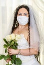 A Jewish bride in a synagogue before a chuppa ceremony during a pandemic, wearing a medical mask and a bouquet of Royalty Free Stock Photo