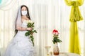 A Jewish bride in a synagogue at a table with flowers before a chuppa ceremony during a pandemic, wearing a medical mask Royalty Free Stock Photo