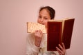 Jewish Girl Reads the Passover Haggadah and Eating Matzah.