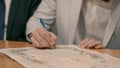 A Jewish groom in a gray suit sits at a wooden table and signs a ketubah.