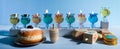 Jewish holiday Hanukkah background with oil Menorah- traditional candelabra, spinning top Dreidel and Doughnut on blue