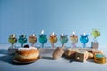 Jewish holiday Hanukkah background with oil Menorah- traditional candelabra, spinning top Dreidel and Doughnut on blue background Royalty Free Stock Photo